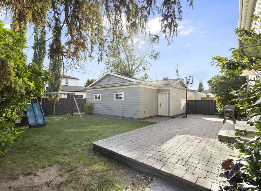 Enjoy outdoor living in this spacious backyard featuring a large paved patio perfect for entertaining and a lush green lawn.