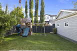 Enjoy outdoor fun in this spacious backyard featuring a vibrant playground with a twisty slide and swings, perfect for children's entertainment.