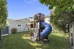 Enjoy outdoor fun in this spacious backyard featuring a vibrant blue tube slide and a classic swing set, perfect for children's entertainment.