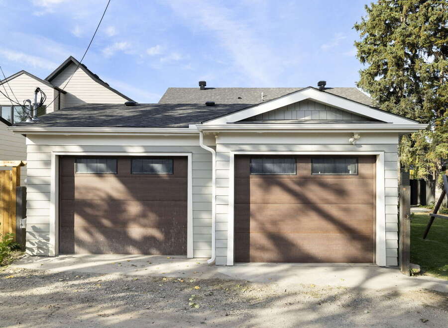 This property features a spacious double garage with two modern, dark wood garage doors, each equipped with a row of rectangular windows for natural light.
