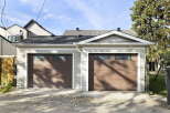 This property features a spacious double garage with two modern, dark wood garage doors, each equipped with a row of rectangular windows for natural light.