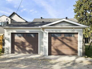 This property features a spacious double garage with two modern, dark wood garage doors, each equipped with a row of rectangular windows for natural light.