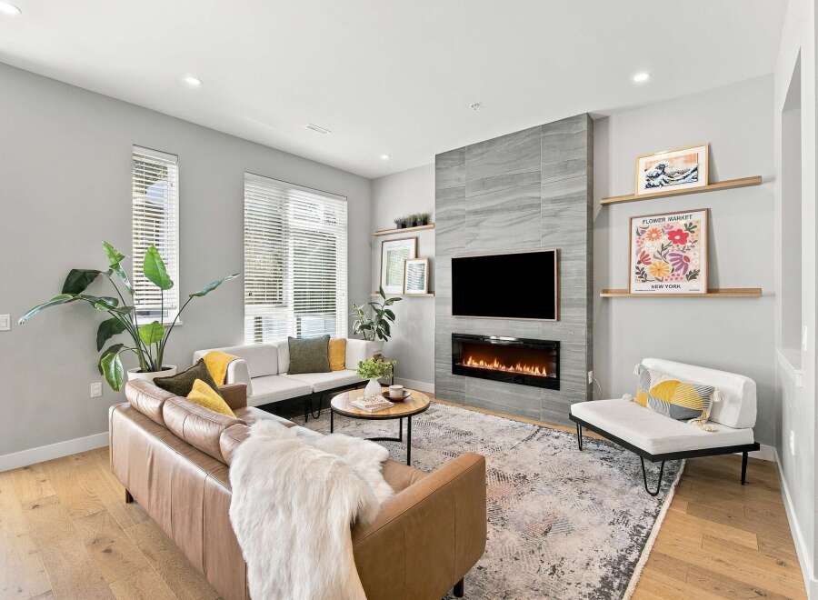 Experience modern living in this stylish living room featuring a sleek fireplace and a large television mounted above it.