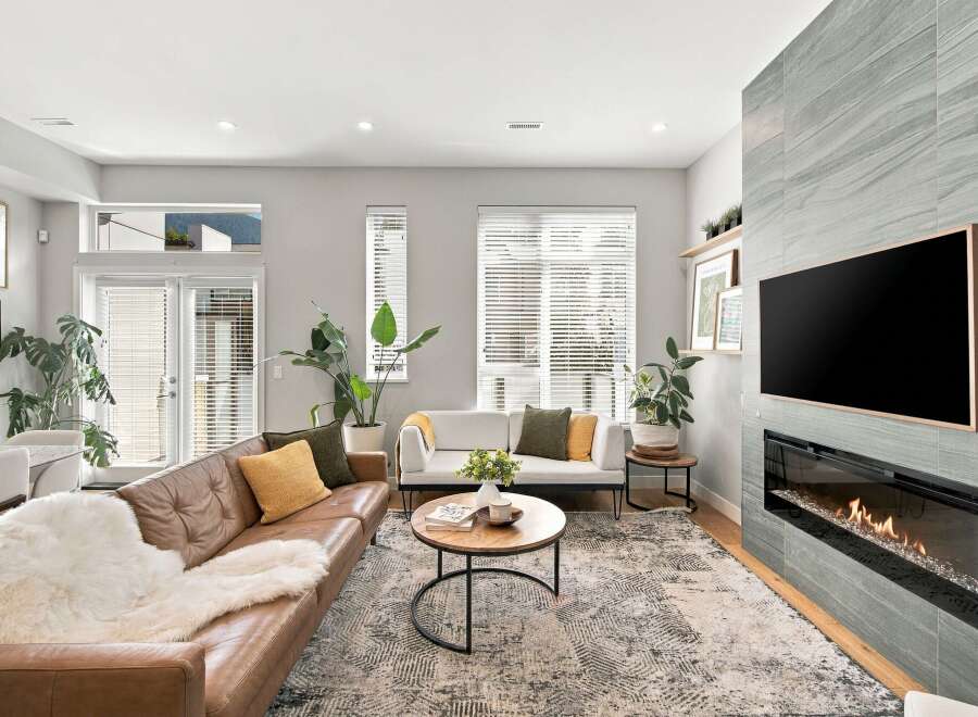 Experience modern living in this stylish living room, featuring a comfortable brown leather sofa adorned with a plush white throw and accent pillows.