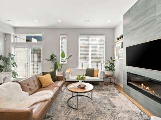 Experience modern living in this stylish living room, featuring a comfortable brown leather sofa adorned with a plush white throw and accent pillows.