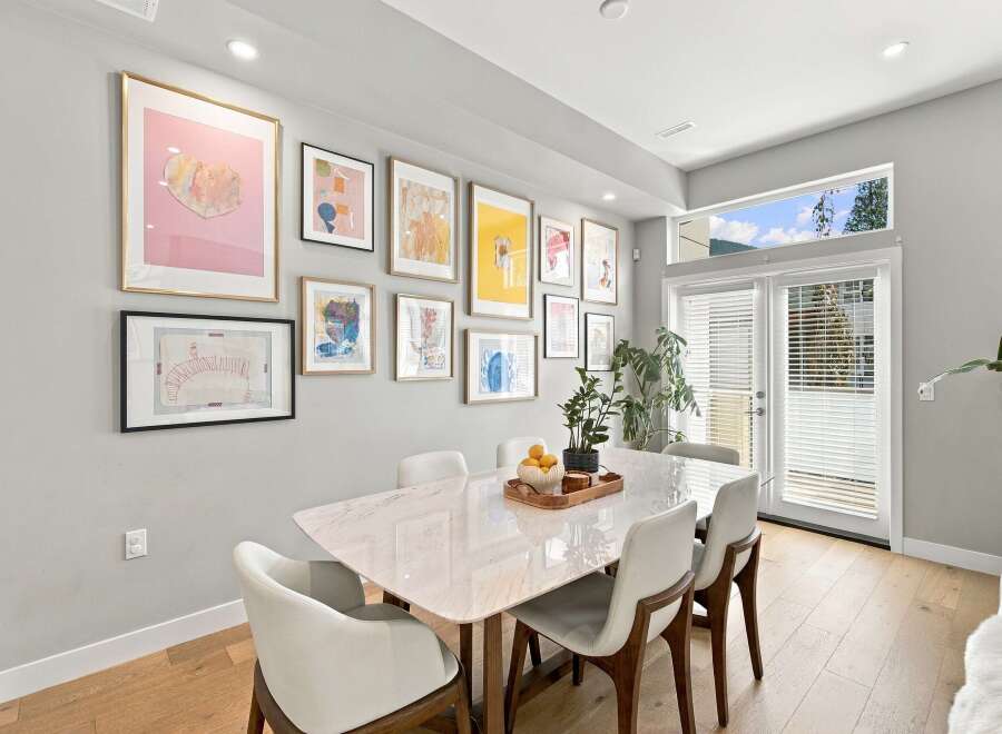 This dining room features a modern marble-top dining table surrounded by elegant white chairs, perfect for hosting guests.