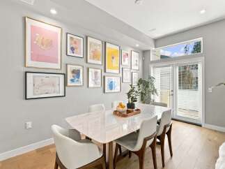 This dining room features a modern marble-top dining table surrounded by elegant white chairs, perfect for hosting guests.