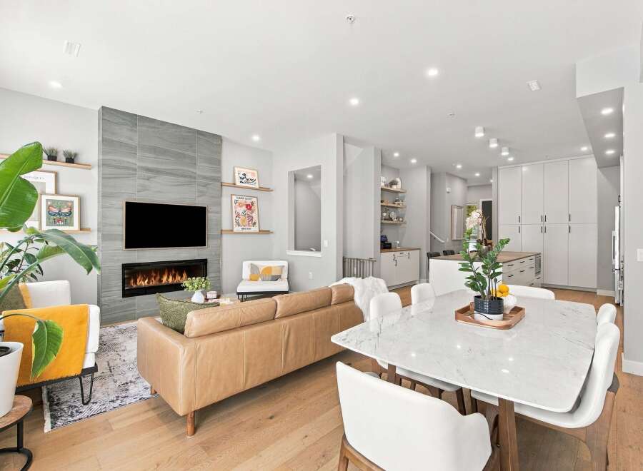 Experience modern living in this stunning open-concept space, featuring a sleek fireplace with a gray tiled accent wall and a large TV.