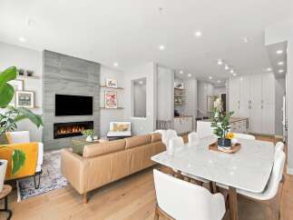 Experience modern living in this stunning open-concept space, featuring a sleek fireplace with a gray tiled accent wall and a large TV.