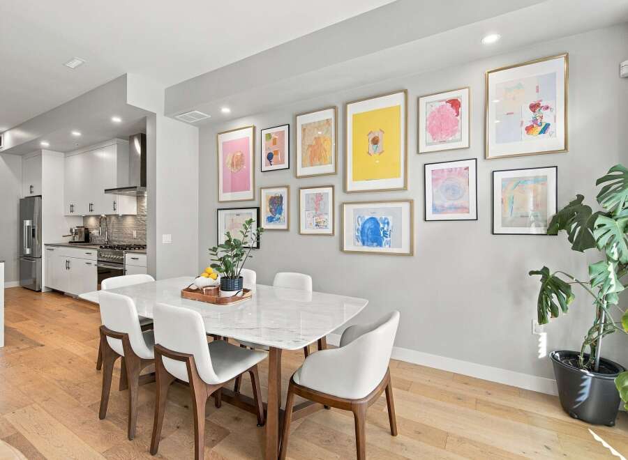 This modern dining room features a sleek marble-top dining table surrounded by elegant white chairs, perfect for family gatherings.