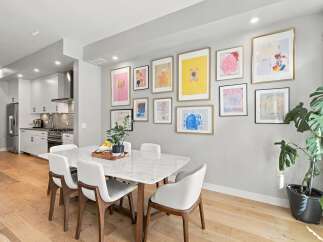 This modern dining room features a sleek marble-top dining table surrounded by elegant white chairs, perfect for family gatherings.