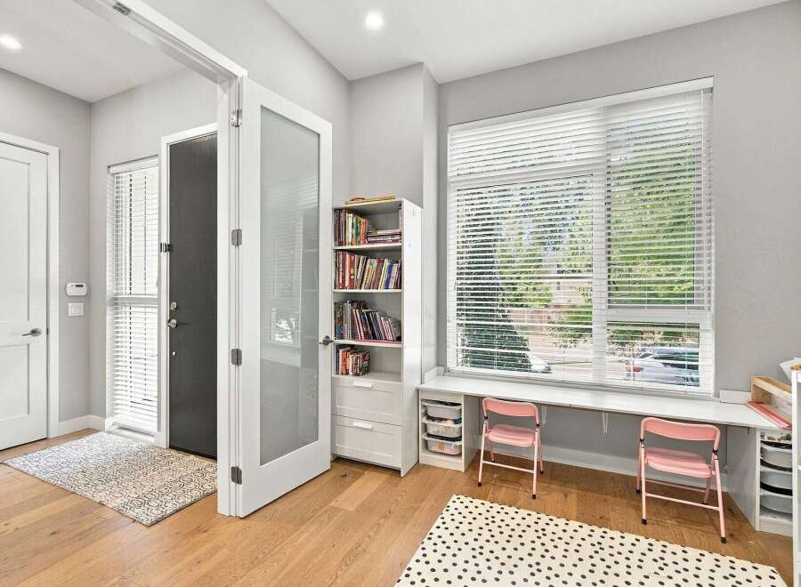 This inviting entryway features a modern aesthetic with a sleek white door and a glass-paneled interior door, leading into a bright space.
