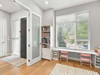 This inviting entryway features a modern aesthetic with a sleek white door and a glass-paneled interior door, leading into a bright space.