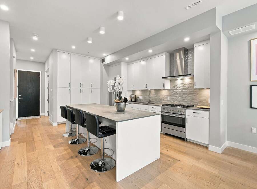 Experience modern living in this stunning kitchen featuring sleek white cabinetry and a spacious island perfect for entertaining.