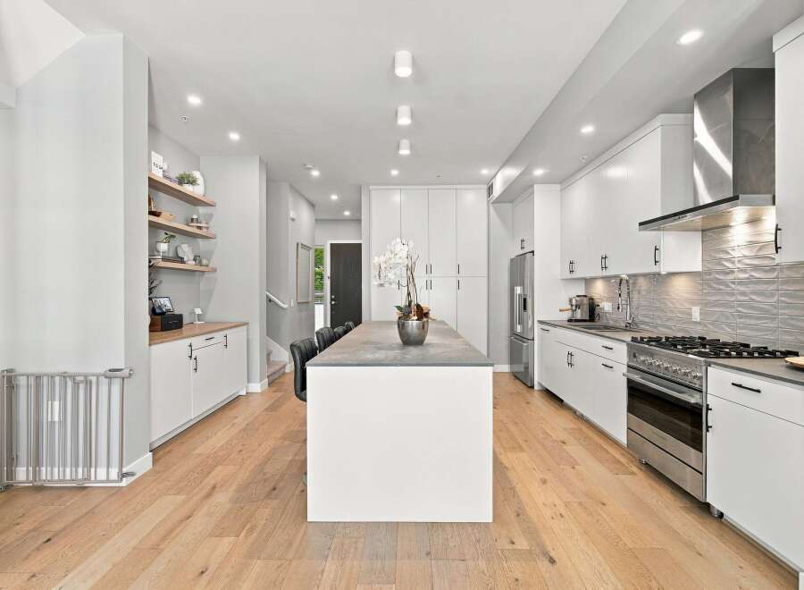 Experience modern living in this stunning kitchen featuring sleek white cabinetry, a spacious concrete island, and a professional-grade gas range.