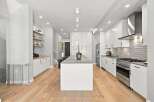 Experience modern living in this stunning kitchen featuring sleek white cabinetry, a spacious concrete island, and a professional-grade gas range.