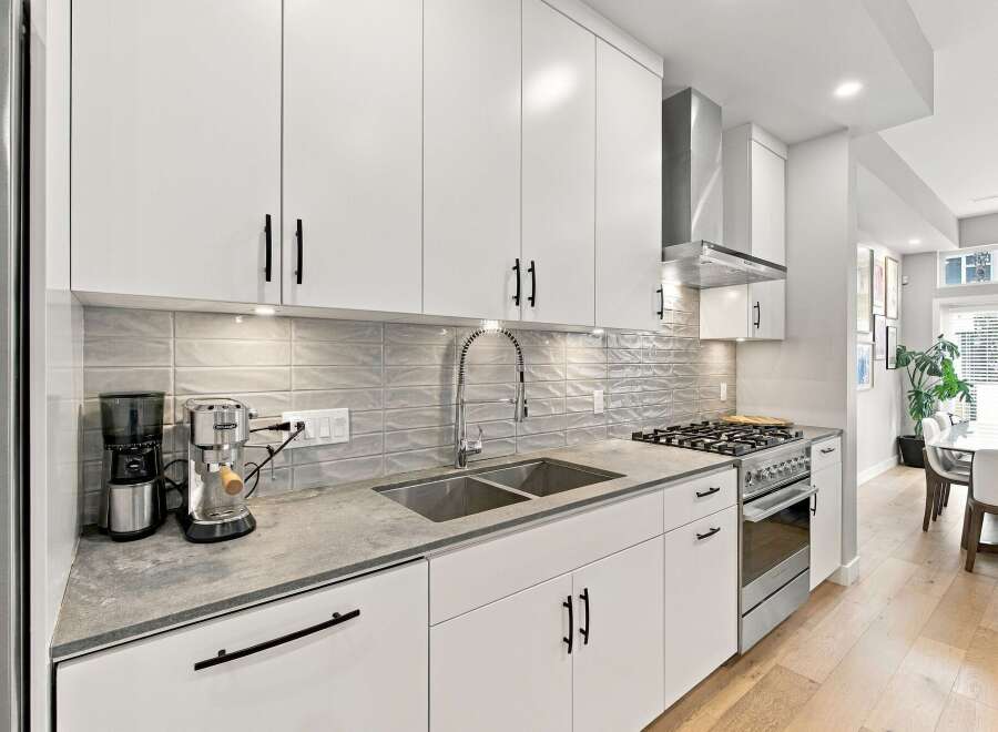 Discover this modern kitchen featuring sleek white cabinetry and a stylish grey subway tile backsplash.