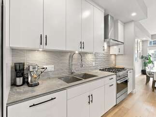 Discover this modern kitchen featuring sleek white cabinetry and a stylish grey subway tile backsplash.