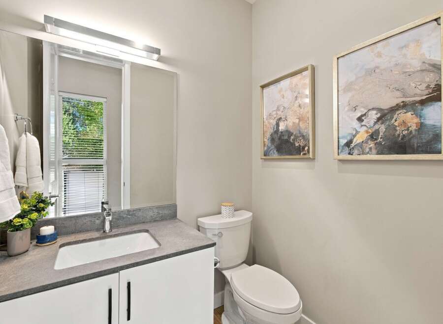 This modern bathroom features a sleek vanity with a stone countertop and a vessel sink, complemented by a large mirror with integrated lighting.