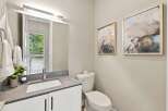 This modern bathroom features a sleek vanity with a stone countertop and a vessel sink, complemented by a large mirror with integrated lighting.