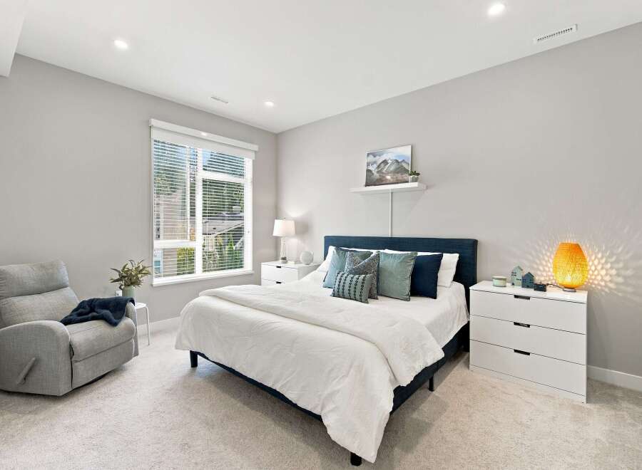 Experience comfort and style in this beautifully appointed bedroom, featuring a plush recliner and a spacious bed adorned with elegant pillows.
