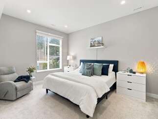 Experience comfort and style in this beautifully appointed bedroom, featuring a plush recliner and a spacious bed adorned with elegant pillows.