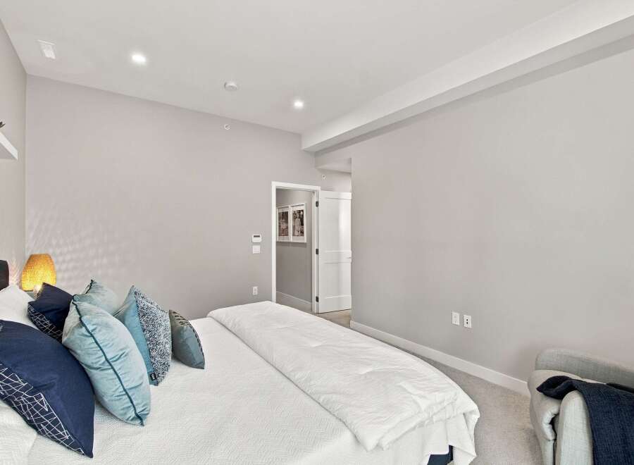 Experience modern comfort in this serene bedroom, featuring a plush king-sized bed adorned with stylish blue and grey accent pillows.