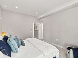 Experience modern comfort in this serene bedroom, featuring a plush king-sized bed adorned with stylish blue and grey accent pillows.