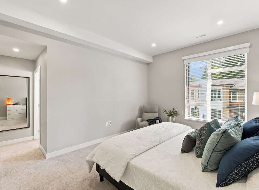 Experience modern comfort in this serene bedroom, featuring a plush king-sized bed adorned with a collection of stylish throw pillows.
