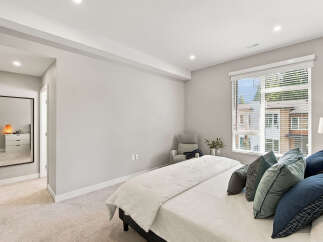 Experience modern comfort in this serene bedroom, featuring a plush king-sized bed adorned with a collection of stylish throw pillows.