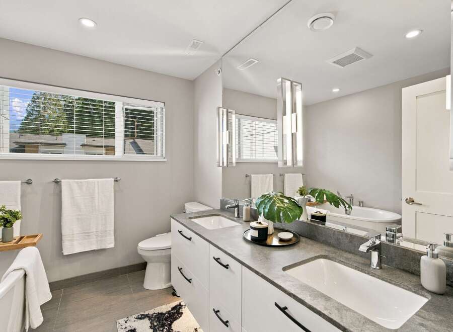 This modern bathroom features a sleek double vanity with a stone countertop and contemporary black hardware.