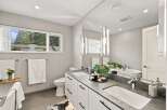 This modern bathroom features a sleek double vanity with a stone countertop and contemporary black hardware.