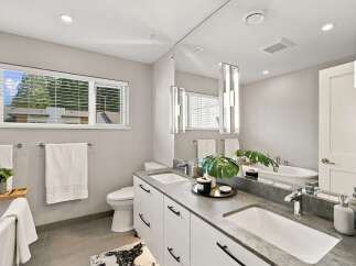 This modern bathroom features a sleek double vanity with a stone countertop and contemporary black hardware.