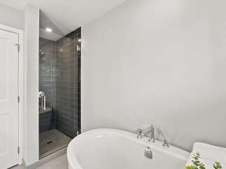 Experience modern luxury in this stunning bathroom featuring a sleek, glass-enclosed shower with dark tiled walls and a rainfall showerhead.