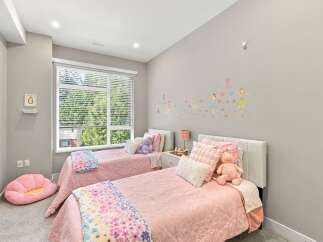 This charming children's bedroom features two twin beds adorned with pink quilted bedding and playful stuffed animals.