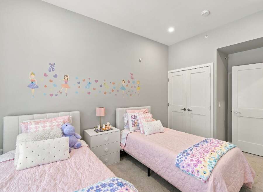 This charming bedroom features two twin beds with plush pink bedding, perfect for a child's or guest room.