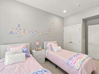 This charming bedroom features two twin beds with plush pink bedding, perfect for a child's or guest room.