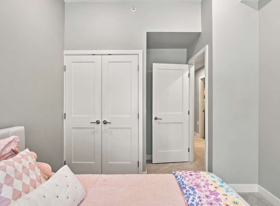 Step into this charming bedroom featuring a comfortable bed adorned with plush pink pillows and a vibrant floral blanket.