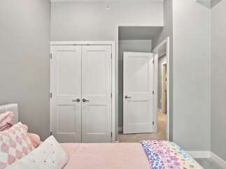 Step into this charming bedroom featuring a comfortable bed adorned with plush pink pillows and a vibrant floral blanket.