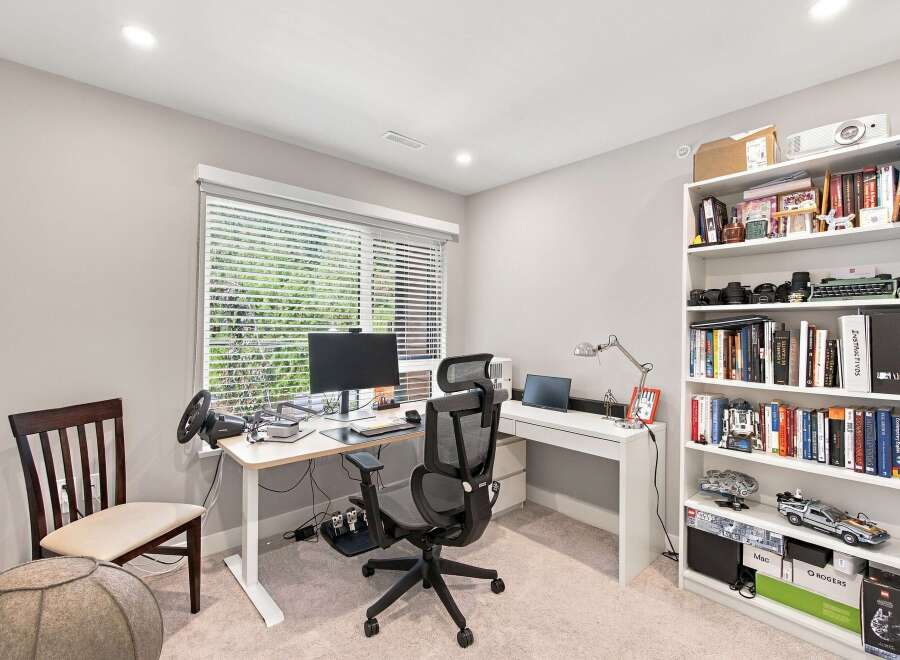 This home office features a modern standing desk equipped with a computer monitor, keyboard, and a racing wheel setup, perfect for productivity or gaming.