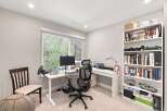 This home office features a modern standing desk equipped with a computer monitor, keyboard, and a racing wheel setup, perfect for productivity or gaming.