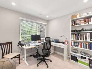 This home office features a modern standing desk equipped with a computer monitor, keyboard, and a racing wheel setup, perfect for productivity or gaming.