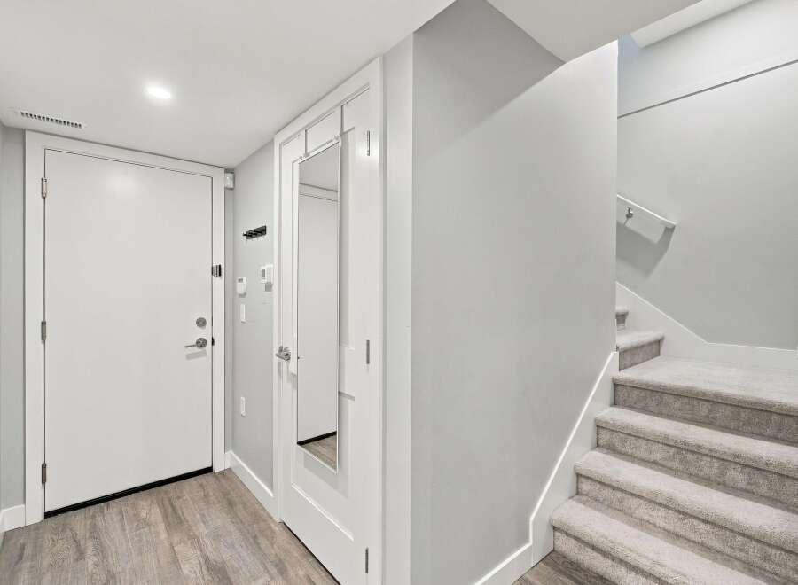 Step into this welcoming entryway featuring a sleek white door and a full-length mirror, perfect for last-minute checks.
