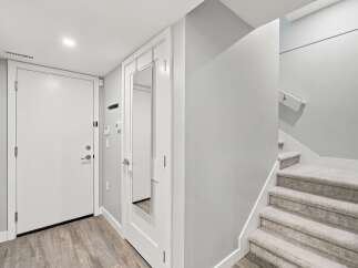 Step into this welcoming entryway featuring a sleek white door and a full-length mirror, perfect for last-minute checks.