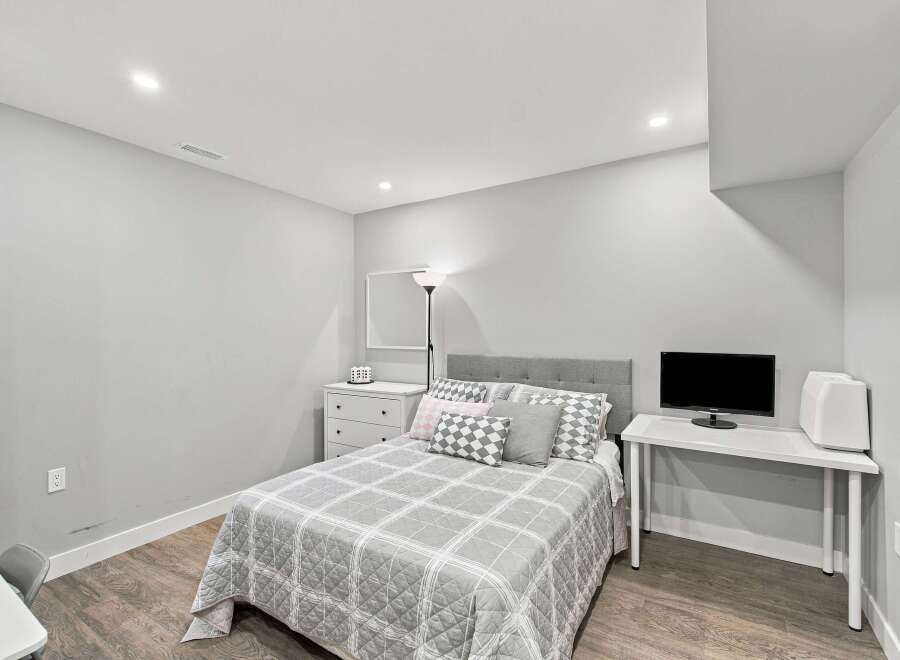 Discover this charming bedroom featuring a comfortable queen-size bed with a stylish upholstered headboard and a coordinating plaid comforter.