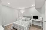 Discover this charming bedroom featuring a comfortable queen-size bed with a stylish upholstered headboard and a coordinating plaid comforter.
