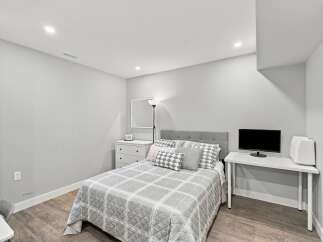 Discover this charming bedroom featuring a comfortable queen-size bed with a stylish upholstered headboard and a coordinating plaid comforter.