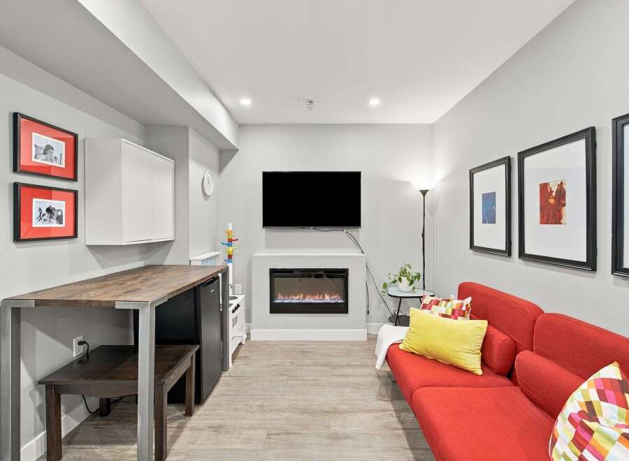This modern living space features a sleek electric fireplace as the focal point, complemented by a large flat-screen TV mounted above.