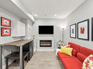 This modern living space features a sleek electric fireplace as the focal point, complemented by a large flat-screen TV mounted above.