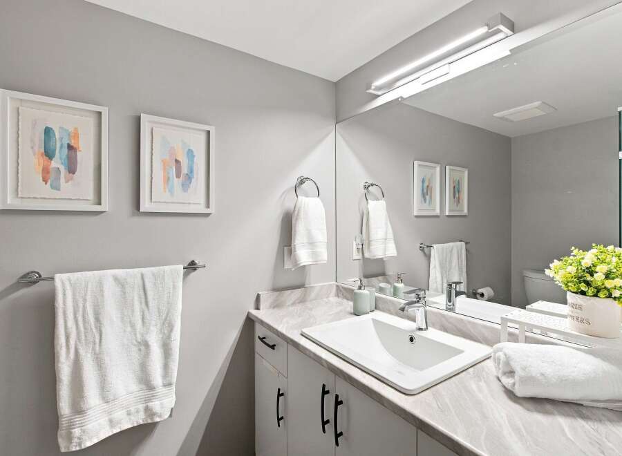 This modern bathroom features a sleek vanity with a marble countertop and a white undermount sink, complemented by minimalist black hardware.